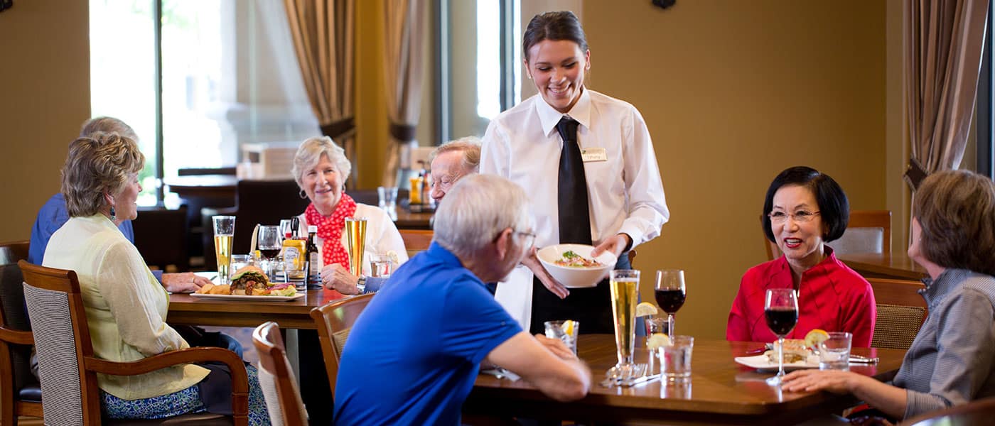 Residents sitting at a restaurant talking to a female server at Stoneridge Creek
