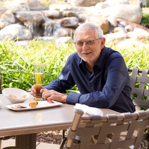 An elderly man having a drink outside