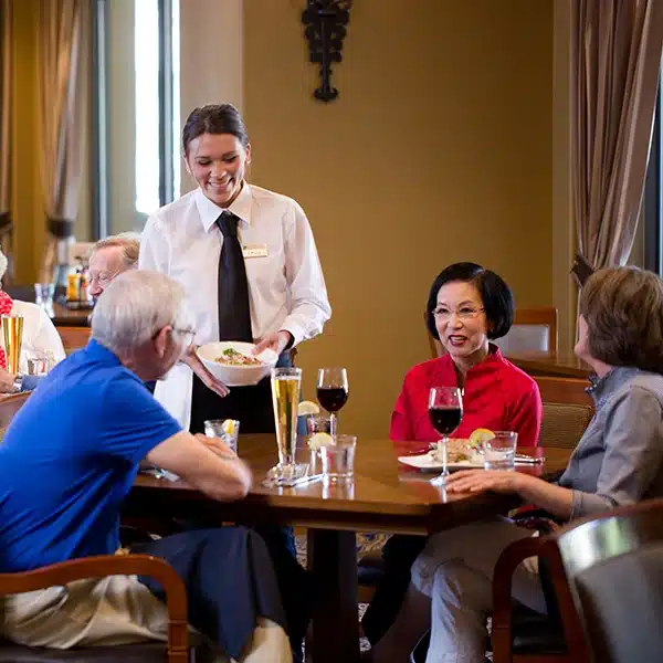 Elderly ladies and gentlemen sitting at a restaurant talking to a female server at Stoneridge Creek