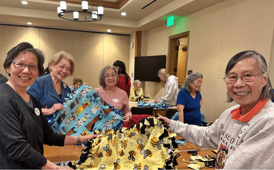 Seniors hold up the soft blanket they made for shelter animals